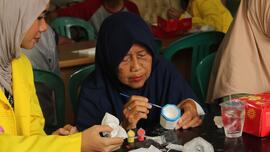 Foto Mahasiswa UI dan Seorang Nenek pada Kegiatan Bakti Sosial Program Kampung Main di Panti Asuhan Bhakti Mandiri dan Panti Werdha Muslim Rumah Oma